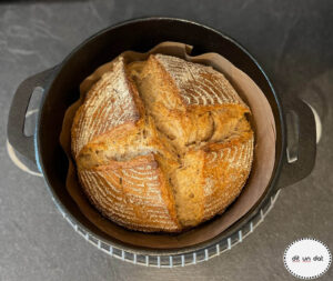 Fertig gebackenes Brot im gusseisernen Topf. Kreuzweise eingeschnitten, die Kruse goldbraun.
