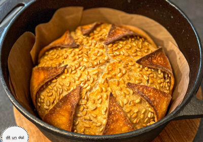 Brot noch im Topf. ein Außenteig ist in 8 Stücke eingeschnitten, die sich vom Innenteig gelöst haben und so wie Blütenblätter aussehen.
